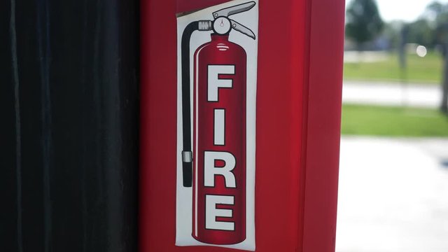 Camera pans to a fire extinguisher box near gas station