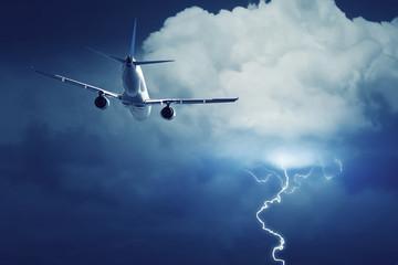 Naklejka premium Passenger airplane flying on stormy sky with dark clouds and lightnings.