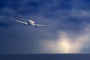 Fototapeta premium Passenger airplane flying above sea on stormy sky with dark clouds and lightnings.