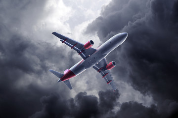 Passenger airplane flying on stormy sky with dark clouds and lightnings.