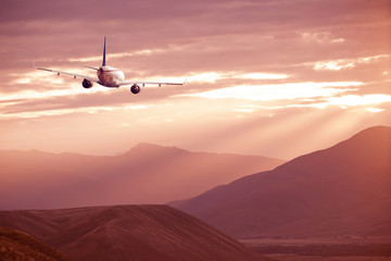 An airplane flying over a mountain range during sunset