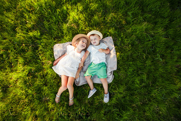 A boy and a girl are lying on the green grass. Top view. Space for text.