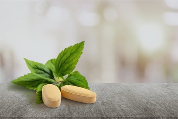 Organic pills with mint leaves on  background