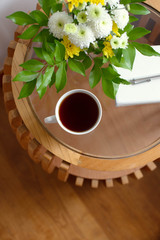 Cup of coffee with a bouquet of flowers on the table. Home interior