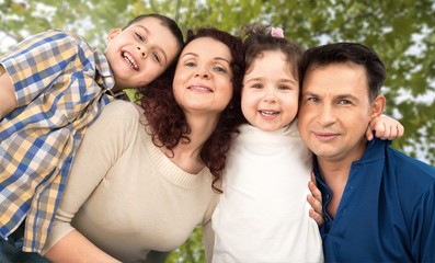 Happy smiling family with daughter over green trees background