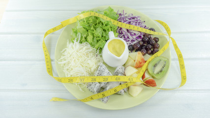 Healthy salad diet food concept, props decoration kiwi, tomatoes, red apple, Dragon fruit, grape, Green  in a plate on wooden background with place for text. Healthy lunch. 