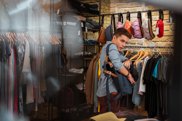 Hiding clothes. Quick professional thief hiding new clothes into his big backpack while stealing in...