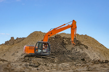 Obraz premium Excavator at the construction site pours a pile of soil