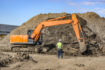 Excavator at the construction site pours a pile of soil