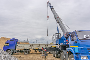 Obraz premium Unloading of building materials by crane at the construction site