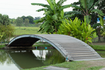 Wooden bridge over the canal in orchard.