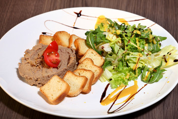 Slice of toasted bread and liver pate on white plate