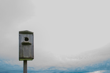 Wooden birdhouse and blue sky with space for text