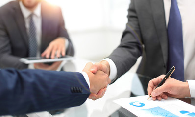 Men shaking hands with smile at office with their coworkers.
