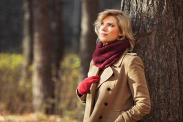 Young blond fashion woman in classic beige coat walking outdoor