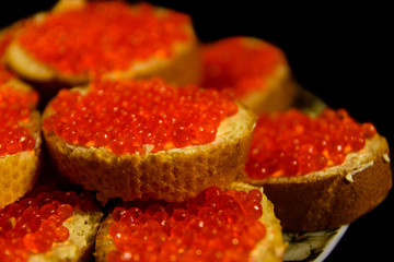 Sandwiches with the red caviar isolated on black background