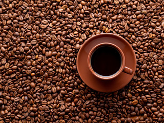brown cup of espresso on background of scattered coffee beans, top view, copy space