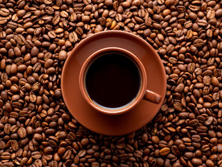 brown cup of espresso on background of scattered coffee beans, top view, close up, macro