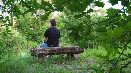 Young Man Sitting on Old Wooden Bench in Park