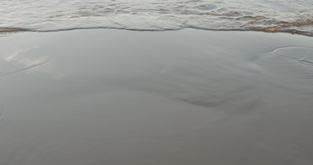 closeup of small waves on a beach at sunset