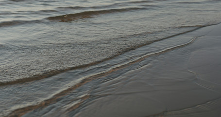 closeup of small waves on a beach at sunset