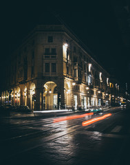 One of the main streets in the center of Turin with the illuminated arcades shooting at night while the red headlights of the cars whizzing giving the sensation of movement 
