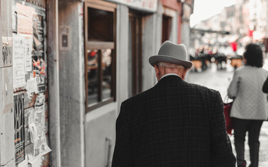 An elderly gentleman, taken back with a gray hat, walks along the canals of Venice