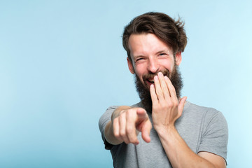 omg. ha-ha. bearded hipster man mocking and laughing at viewer pointing finger and covering mouth....