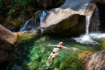 Woman enjoying a swim in the glacier river running down the beautiful Canadian canyon. Taken in...