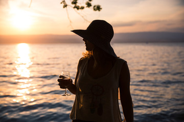 Silhouetted Woman Holding a Glass of Wine and Wearing a Transparent T-Shirt at Sunset