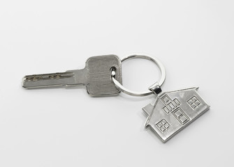 Key and keychain in the shape of a house isolated on white background.