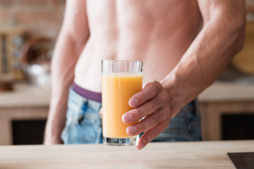 detox diet drink for slimming and weightloss. sexy fit muscled bare chested unrecognizable man holding a glass of healthy beverage