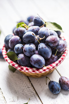Sweet ripe plums in basket on garden table