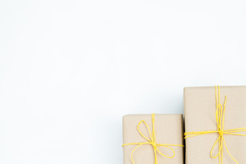 christmas presents in gift boxes wrapped in craft paper and tied with a yellow twine. two packages on white background with free space