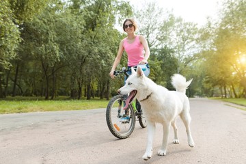 Young teenage girl on bicycle with dog in the park