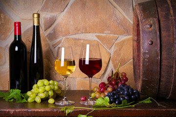 Red and white wine with  grapes beside old cask in wine cellar. Glasses and bottles of wine © freeskyline