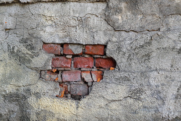 An old brick wall with gray plaster. Red brick.