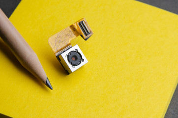 small camera lens part from smartphone on sticky paper compare with pencil - 220921008