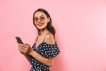 Naklejka premium Side view of Smiling brunette woman in dress and sunglasses