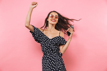 Cheerful brunette woman in dress and sunglasses dancing