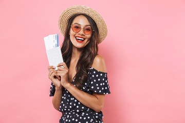 Happy brunette woman in straw hat and sunglasses holding passport