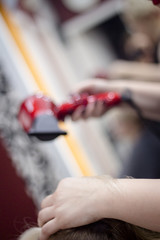 Hairdresser drying hair with hand dryer