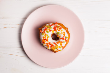 donut in sugar glaze with candied fruits on a pink plate