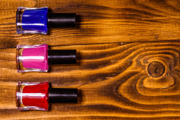 Different nail polishes on a wooden table. Top view