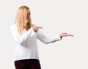 Middle age blonde woman with white shirt holding copyspace imaginary on the palm to insert an ad on...
