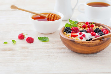 granola with berries on white wooden background