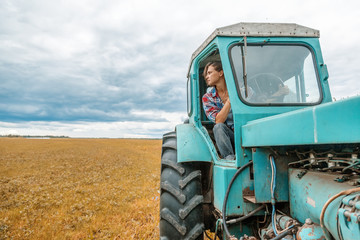 Young beautiful girl working on a tractor in the field, unusual work for women, gender equality concept