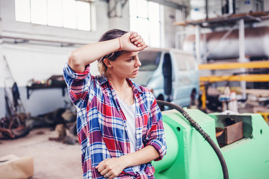 Young beautiful girl working in a workshop for repair of cars and appliances, not female profession, the concept of gender equality, tired from hard work
