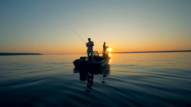 Fishing process of two anglers in a sunrise waterscape