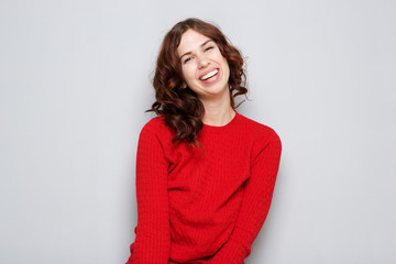 Fototapeta premium smiling young woman in red sweater by gray wall